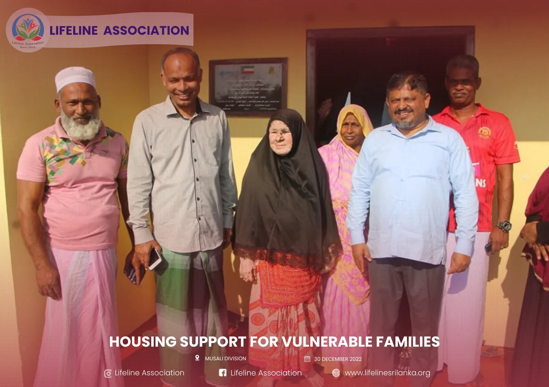 The recipient family standing with representatives outside the new home